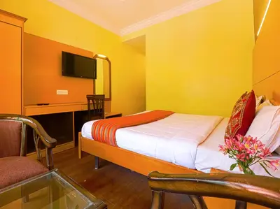 a hotel room with a bed and a desk and a tv at The Byke Sunshine Grand in Ooty