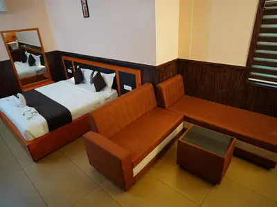 a bedroom with a couch and a bed with a mirror at ABUDHABI RESIDENCY in Palakkad