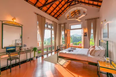 a bedroom with a large bed in a room with windows at Zostel Homes Wayanad, Vythiri in Wayanad