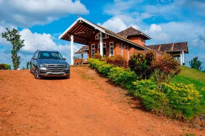 a car parked in front of a house on a dirt road at Zostel Homes Wayanad, Vythiri in Wayanad