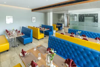 a restaurant with blue and yellow chairs and tables at Oshin Wayanad in Wayanad