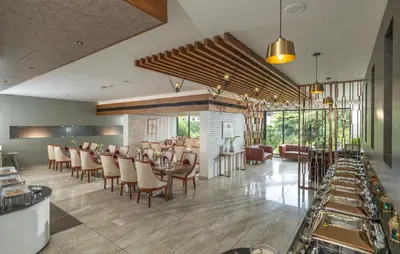 a dining room with tables and chairs in a restaurant at Oshin Wayanad in Wayanad
