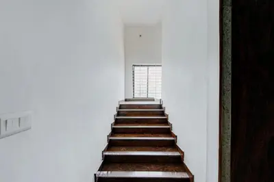 a stairway in a white room with wooden steps at Super Townhouse Mysore City Centre Formerly Hotel Mahendra in Mysore