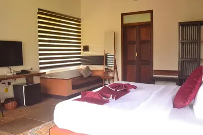 a bedroom with a bed and a desk and a television at Aalterra by The Almanac in Wayanad