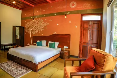 a bedroom with a bed and a couch and a chair at Aalterra by The Almanac in Wayanad