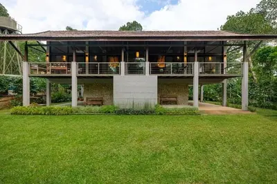 a large building with a balcony and a lawn at amã Stays & Trails - The Old Cattleshed, Wayanad in Wayanad
