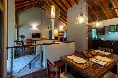 a dining room with a table and a kitchen at amã Stays & Trails - The Old Cattleshed, Wayanad in Wayanad