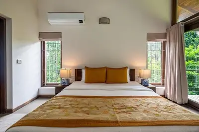 a bedroom with a large bed and two windows at amã Stays & Trails - The Old Cattleshed, Wayanad in Wayanad