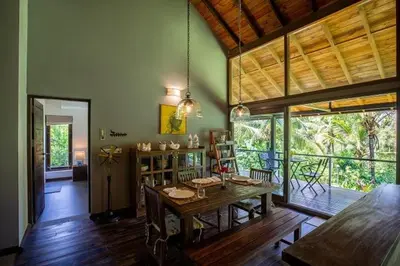 a living room with a wooden table and a dining room at amã Stays & Trails - The Old Cattleshed, Wayanad in Wayanad