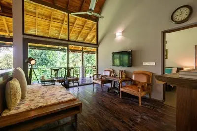 a living room with furniture and a clock on the wall at amã Stays & Trails - The Old Cattleshed, Wayanad in Wayanad