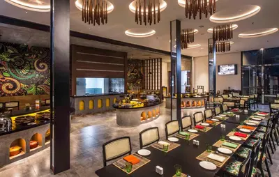 a restaurant with long tables and a bar at GReaT Trails Wayanad by GRT Hotels in Wayanad