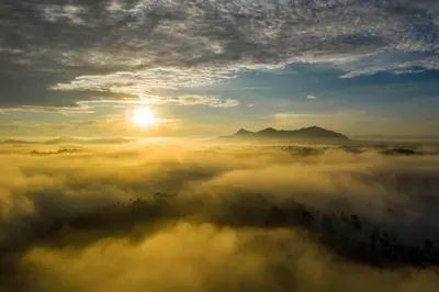 a view of the sun rising over a fog covered field at GReaT Trails Wayanad by GRT Hotels in Wayanad