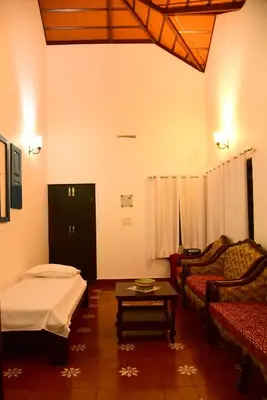 a room with a bed and a couch and a table at Nivaasana Bed & Breakfast in Kalpetta