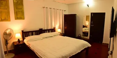 a bedroom with a bed with white sheets and a mirror at Nivaasana Bed & Breakfast in Kalpetta