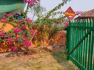 a green fence with pink flowers next to a house at Nivaasana Bed & Breakfast in Kalpetta