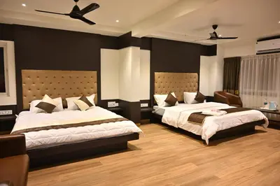 a bedroom with two beds and a ceiling fan at Mysore Royale in Mysore
