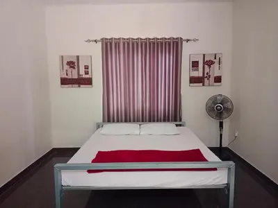 a bedroom with a white bed with a red blanket at Kalamana Serene in Chāvakkād