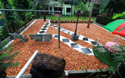a garden with a checkered floor and an umbrella at NARMADA POOL VILLA (KAVERI) in Perintalmanna