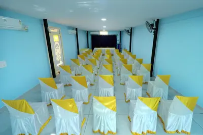 a room with yellow and white chairs and a stage at NARMADA POOL VILLA (KAVERI) in Perintalmanna