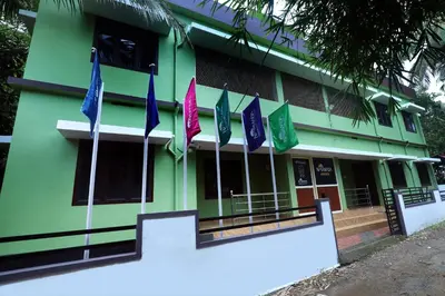a green building with flags in front of it at NARMADA POOL VILLA (KAVERI) in Perintalmanna