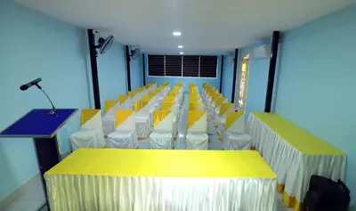 a room with rows of chairs and a table with a microphone at NARMADA POOL VILLA (KAVERI) in Perintalmanna