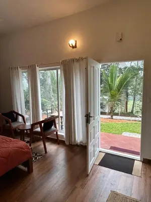 a bedroom with a door open to a patio at Silver Oak By Exuberance Stays (Independent Holiday Home) in Wayanad