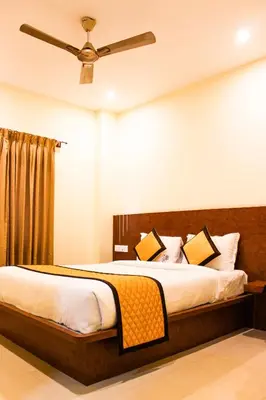 a bedroom with a bed with a ceiling fan at Sai Vihaar Inn & Suites in Mysore