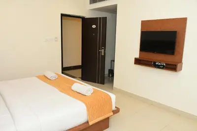 a hotel room with a bed and a flat screen tv at Sai Vihaar Inn & Suites in Mysore
