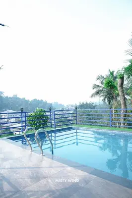 a swimming pool with a fence and trees in the background at Vythiri Misty Wind Holiday Homes in Vythiri