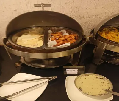 a pan with food and a plate of food at Mango Hill Central Ooty in Ooty