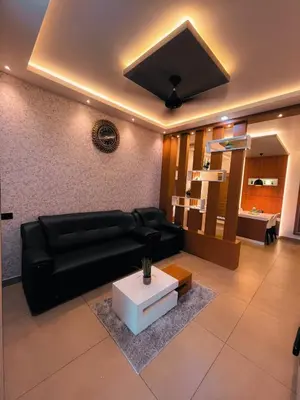 a living room with a black couch and a table at BBC Luxury Apartments in Perintalmanna