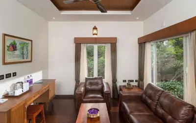 a waiting room with a leather couch and a desk at Jeevess Retreat Wayanad in Wayanad