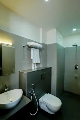 a bathroom with a white toilet and a sink at SATRA WAYANAD in Kalpetta