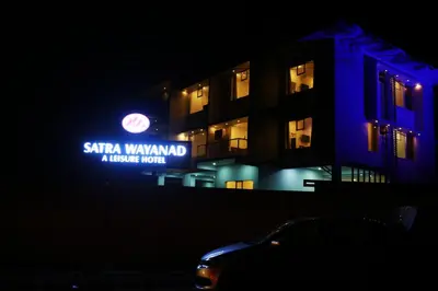 a building with a sign on it at night at SATRA WAYANAD in Kalpetta