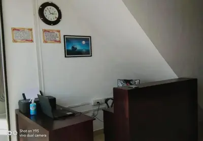 a office with a clock on the wall and a desk at Emirates Residency in Pudunagaram