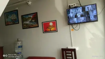 a flat screen tv hanging on a wall with pictures at Emirates Residency in Pudunagaram