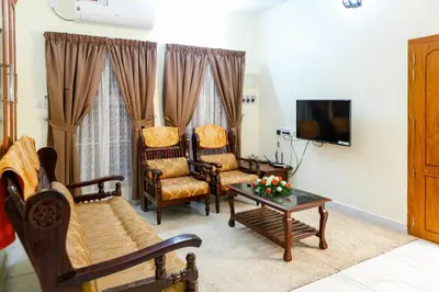 a living room with chairs and a table and a tv at Belljem Homes -your own private resort -5 BHK in Trichūr