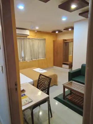 a living room with a table and a green couch at GRACE RESIDENCY in Tirūr