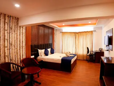 a hotel room with a bed and a table and chairs at Vista Suites Doddabetta Ooty By Bestinn Leisure in Ooty