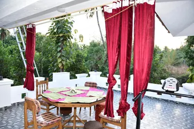 a table and chairs on a patio with red curtains at Oceangreen cottage in Kannur
