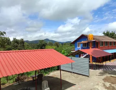 a house with a red roof and a blue building at Lake View Homestay by StayApart in Madikeri