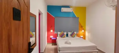 a room with two beds and a colorful wall at goSTOPS Coorg in Madikeri