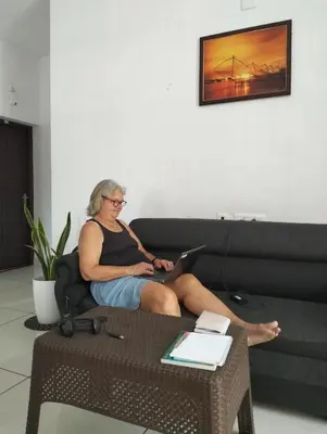 a woman sitting on a couch with a laptop at Bachan's Casa The Private Pool Villa Cherai in Cherai Beach