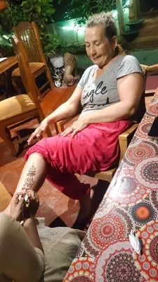 a woman sitting on a chair with a tattoo on her leg at Ambadi's villa -Lake view resort in Pallipuram