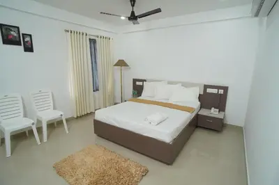 a bedroom with a large bed and two chairs at SN ROOMS in Perumbavoor