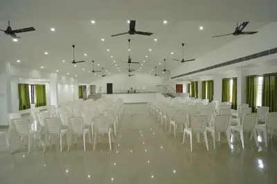 a large room with white chairs and a large room with a room at SN ROOMS in Perumbavoor