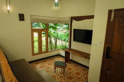 a living room with a couch and a television at Maple Ash Resort in Vayittiri