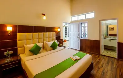 a bedroom with a large bed with green and yellow pillows at Rosewood by Nature Resorts and Stays in Ooty