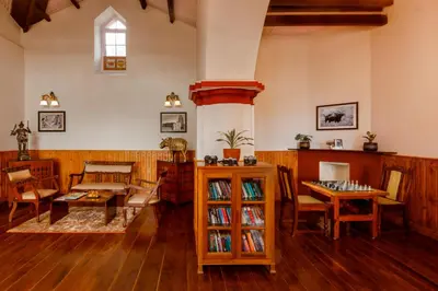 a living room with wooden floors and a table and chairs at Rosewood by Nature Resorts and Stays in Ooty