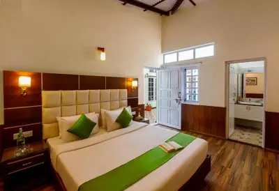 a bedroom with a large bed with green pillows at Rosewood by Nature Resorts and Stays in Ooty
